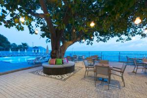 a tree with chairs and tables next to a pool at Floria Beach Hotel in Alanya +18 photos