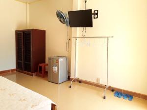 a room with a bed and a tv on the wall at Ngoc Sang Guesthouse in Mui Ne