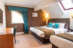 a hotel room with two beds and a desk at Ufford Park Resort in Woodbridge