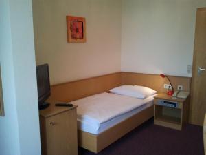 ein kleines Schlafzimmer mit einem Bett und einem TV in der Unterkunft Gästehaus Galant in Esslingen