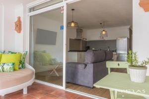 Una sala de estar con un sofá y una puerta corrediza de vidrio. en Apartamento Atlántico Playa 1, en Puerto Naos