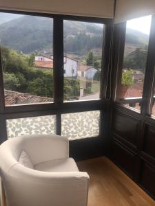 a white chair in a room with a large window at Apartamentos Casa de la Abuela in Potes