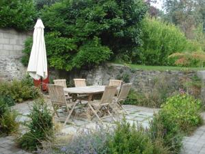 einen Tisch, Stühle und einen Sonnenschirm in einem Garten in der Unterkunft Maison d'Hôtes Augès in Tréguier