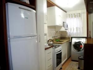 cocina con nevera blanca y lavadora en Apartamento Aconchegante + Bikes, en Gramado