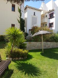 a park with a bench and an umbrella in a yard at Costa Esuri in Ayamonte