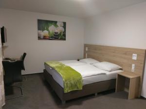 a bedroom with a bed with a green blanket on it at Gasthaus Pension Rezatgrund in Windsbach