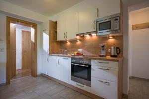 a kitchen with white cabinets and a microwave at Appart Gitti in Gerlos