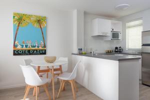 a kitchen with a table and white chairs and a kitchen with a table at Ocean View Beach Escape - Top Floor Apartment, Mt Maunganui Base in Mount Maunganui