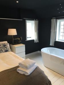 een slaapkamer met een bad, een bed en ramen bij The Tailor's Flat in Rye
