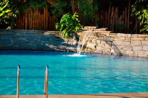 a fountain in a pool with blue water at Hotel Santa Amalia in Vassouras