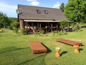 a log cabin with two benches in the grass at Likimo ratas in Paliepis