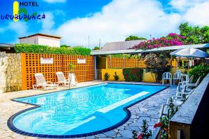a swimming pool with chairs and an umbrella at Hotel Urubupunga in Ilha Solteira