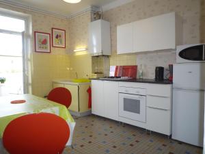 a kitchen with white appliances and a table with red chairs at Appartement Hello in Metz