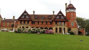 ein großes Backsteingebäude mit einem Grasfeld davor in der Unterkunft Ondarreta Beach Apartment con parking free y Aire acondicionado in San Sebastián