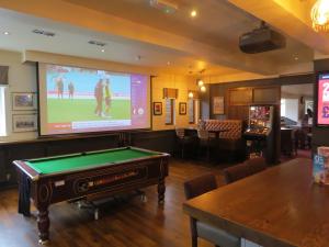 a room with a pool table and a large screen at Highwayman Hotel in Dunstable