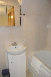 a white bathroom with a sink and a bath tub at Seven Dials Apartments Bedford Street in London