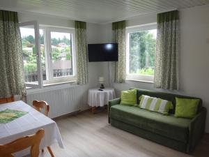a living room with a green couch and two windows at Ferienbungalow in Seeboden