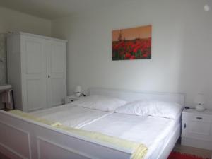 ゼーボーデンにあるFerienbungalowの白いベッド1台付きのベッドルーム1室(壁に絵画付)
