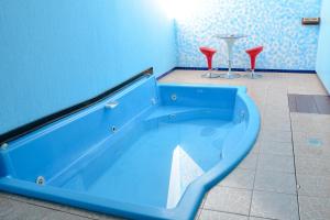 a blue tub in a bathroom with two red chairs at MOTEL LIBIDUS - Foz do Iguaçu in Foz do Iguaçu