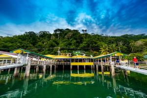 a pier with yellow and green buildings on the water at Banana Bay Marina in Golfito