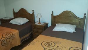 a bedroom with two beds and a table with a lamp at Hospedaria D. Fernando in Viseu