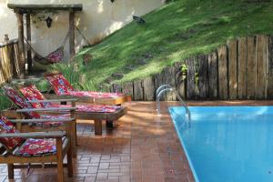 a backyard with a swimming pool and chairs and a fence at Pousada Villa Parahytinga in São Luiz do Paraitinga
