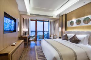 una camera d'albergo con un grande letto e una TV di Wyndham Grand Plaza Royale Wenchang a Wenchang