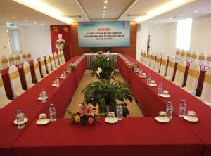 una sala de reuniones con mesas y sillas rojas y una pantalla en Khách sạn Công Đoàn Quảng Bá, en Hanói