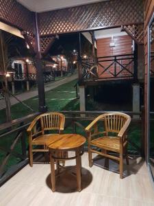 two wooden chairs and a table on a porch at Perhentian Island Cocohut Long Beach Resort in Perhentian Islands