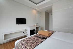 Una habitación de hotel con una cama y un televisor. en Pondok Nyaman 15, en Denpasar