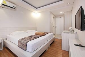 a white bedroom with a large bed and a television at Pondok Nyaman 15 in Denpasar