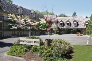un cartello di una locanda universitaria di fronte a un edificio di Riverside Inn a Grants Pass