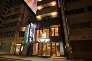 ein Gebäude mit einem aacco Store in einer Stadtstraße nachts in der Unterkunft HOTEL Cargo Shinsaibashi in Osaka
