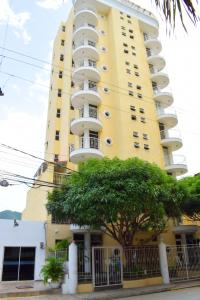 un edificio amarillo con un árbol delante de él en Santa Marta Apartamentos Salazar - Maria Paula, en Santa Marta