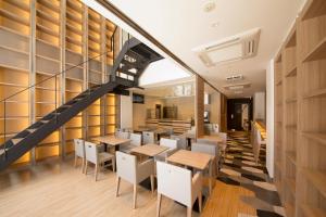 a restaurant with a staircase and tables and chairs at HOTEL Cargo Shinsaibashi in Osaka