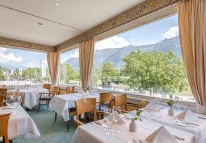 un restaurante con mesas, sillas y ventanas grandes en Metropole Swiss Quality Hotel, en Interlaken