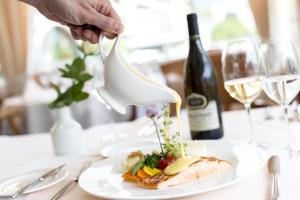 a person pouring white wine into a plate of food at Metropole Swiss Quality Hotel in Interlaken