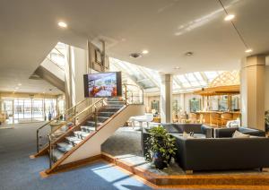 eine Lobby mit einer Treppe und einem TV an der Wand in der Unterkunft Metropole Swiss Quality Hotel in Interlaken