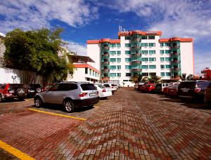 un estacionamiento con autos estacionados frente a un edificio en Hotel El Marqués en Atacames