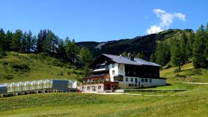 a building on a hill next to a train at Hotel Alpen Arnika in Tauplitzalm