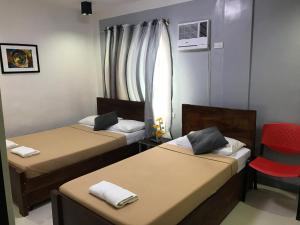 a room with two beds and a red chair at Alzeah's Place Room for Rent in Tagaytay
