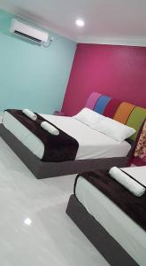 two beds in a room with a colorful wall at Iz Village in Kuala Besut