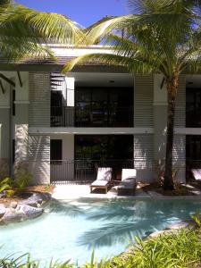 a swimming pool in front of a house with palm trees at Penthouse 239 at Sea Temple Port Douglas in Port Douglas