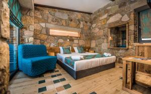 a bedroom with a bed and a chair in a stone wall at Keros Blue - Luxury in Wilderness in Kalliópi