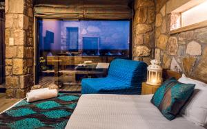 a bedroom with a bed and a chair and a table at Keros Blue - Luxury in Wilderness in Kalliópi