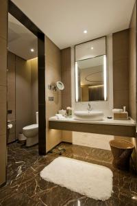 a bathroom with a sink and a toilet and a mirror at Cachet Boutique Kunming Artime in Kunming