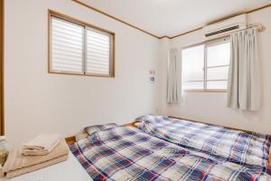 a bed in a room with two windows at Awaza House 2 in Osaka