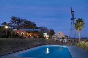 a swimming pool in front of a house at De Zeekoe Guest Farm in Oudtshoorn