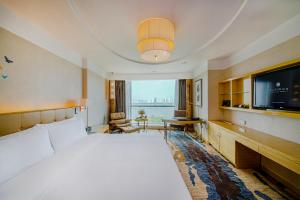 a hotel room with a large bed and a flat screen tv at Pullman Linyi Lushang in Linyi