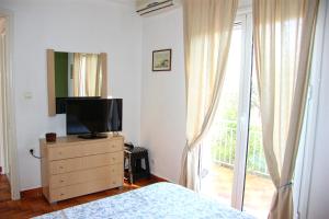 a bedroom with a television on a dresser with a window at Eleni Houses in Kómboi